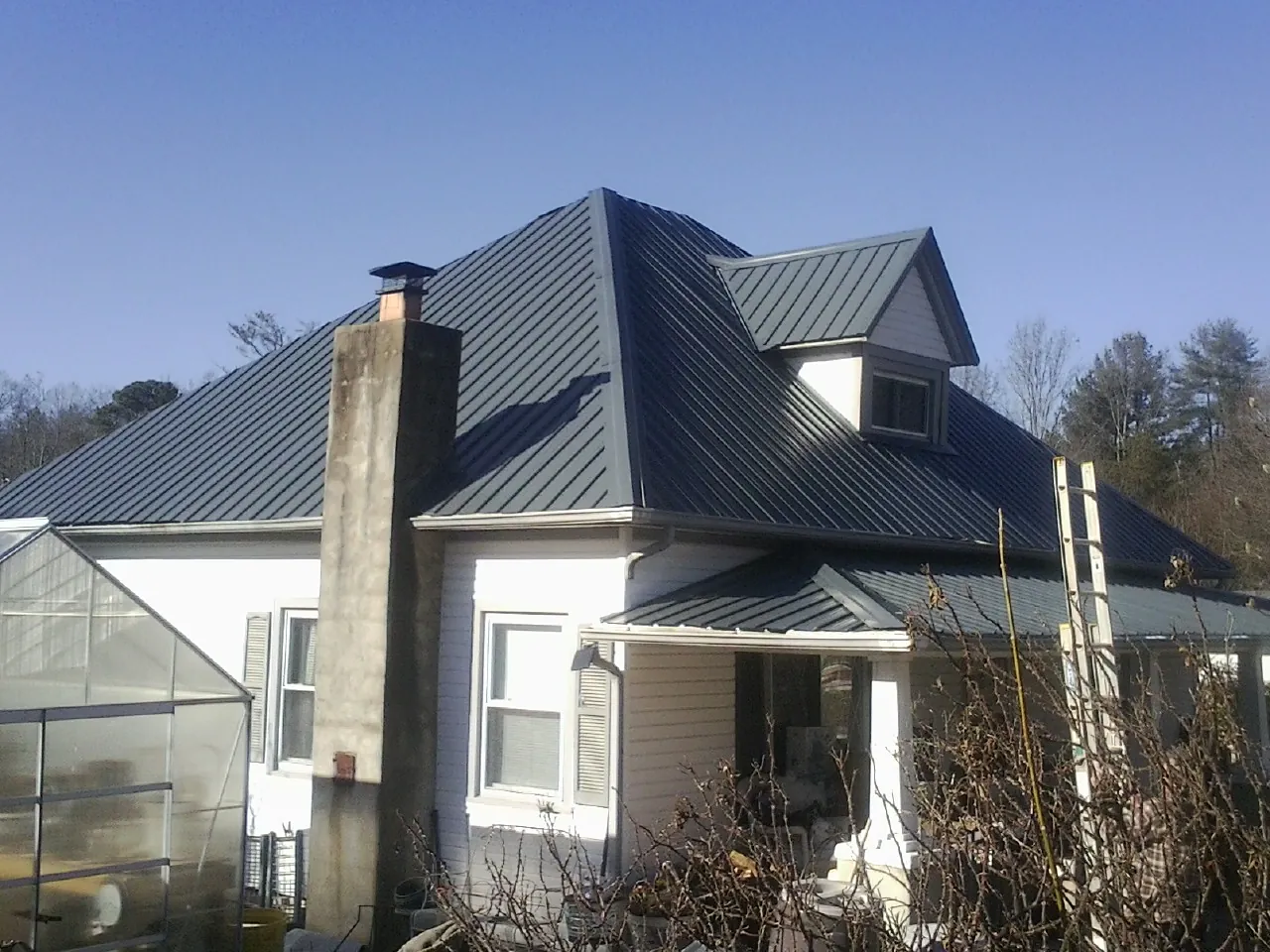 Dark blue standing seam metal roof on a white farmhouse with dormer — Slate & Tile Roof Repair by Roofing Brothers in Scott