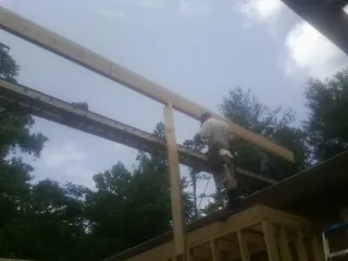 Carpenter setting a ridge beam over a new addition frame — Ice Dam Removal by Roofing Brothers in Scott