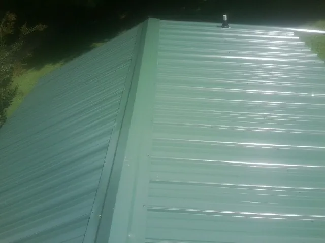 New green metal panels meeting at the ridge of a roof — Flat Roof Repair work by our crew in Scott