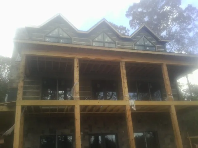 Dormers and porch framing on a large log home under construction — Roof Coating work by our crew in Scott