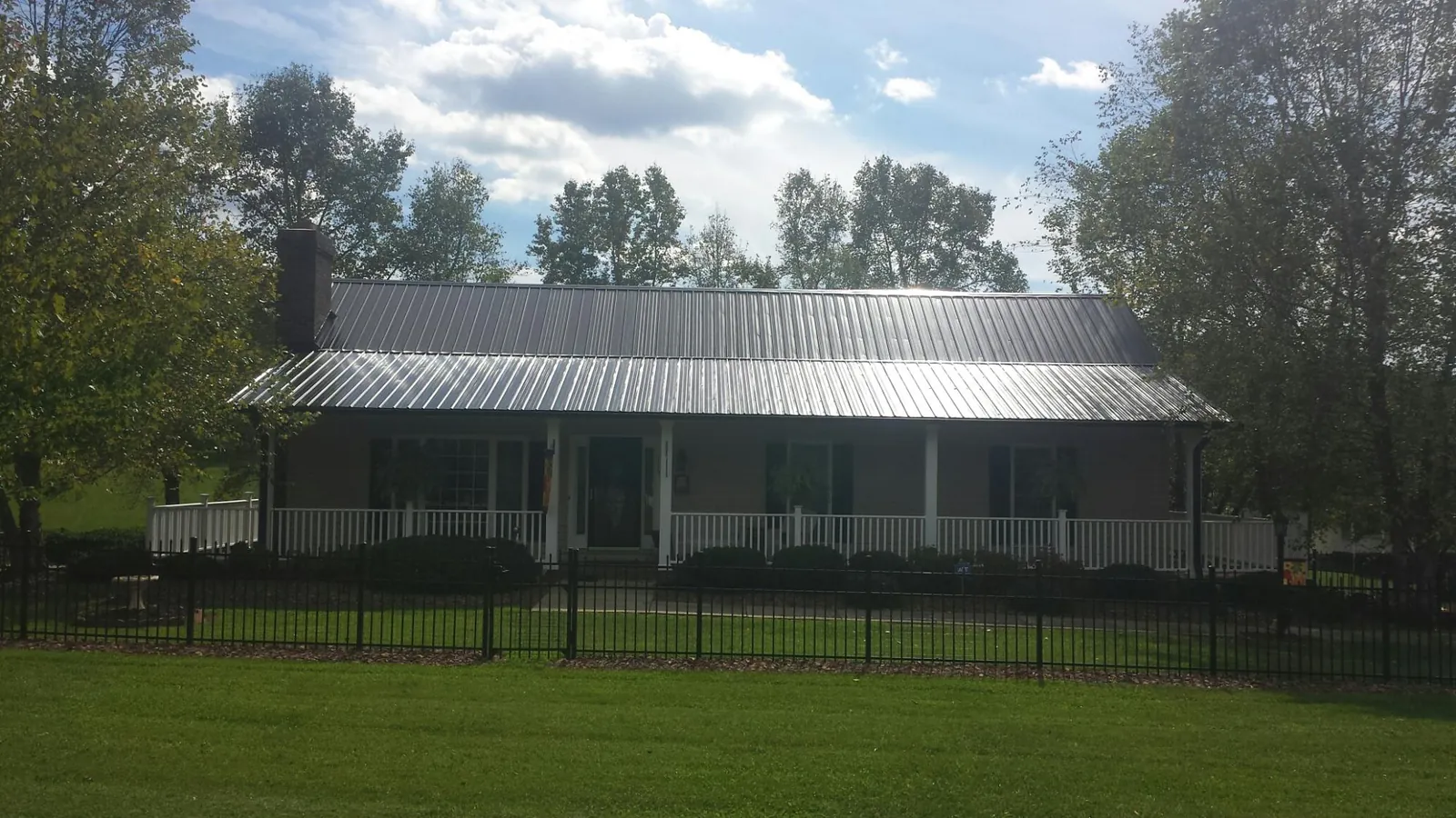 Gray metal roof on a brick ranch with a full width front porch — Gutter Guard Installation work by our crew in Scott